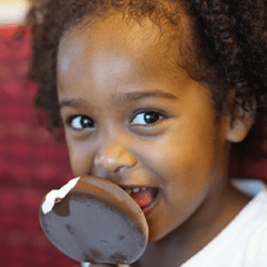African American girl tasting a chocolate dipped vanilla ice cream dessert from Dairy Queen