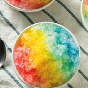 Port Aransas snow cone with multiple colors and flavors poured on it to make a rainbow