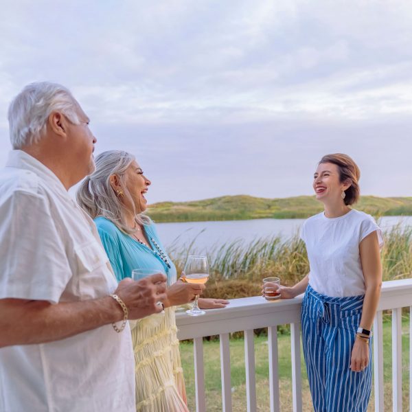 Friends Sharing Drinks On Porch Of Palmilla Beach Home